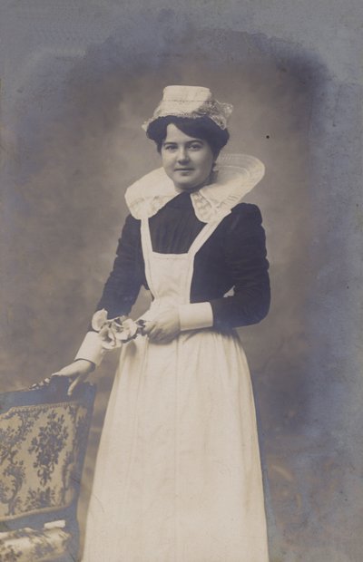 Niña joven, ¿mucama?, sosteniendo un pequeño ramo de flores de French Photographer
