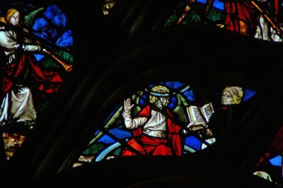La ventana rosa oeste que representa una escena del Libro de Apocalipsis: un ángel (en un arco iris) dando a San Juan un libro abierto (10:1,8) de French School