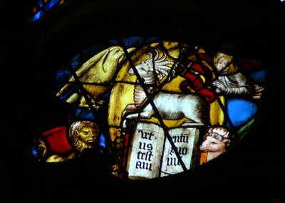 La ventana rosa oeste que representa una escena del Libro de Apocalipsis: cordero con siete cuernos y siete ojos abre el libro. Nota los símbolos de los 4 evangelistas (5:7) de French School