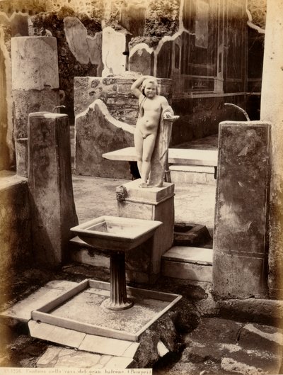 Una fuente compuesta por una escultura de un niño desnudo. La fuente está en la Casa del Balcón colgante, en Pompeya de Giorgio Sommer