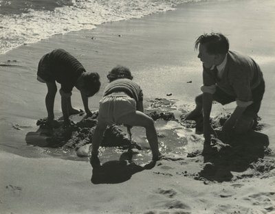 Tres niños jugando con arena en la playa. de Godfrey Macdominic