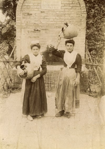 Dos mujeres jóvenes con trajes tradicionales y jarras de terracota cerca de un pozo, Las Marcas, Italia, hacia 1910. de Italian Photographer