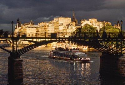 Nubes oscuras mientras un barco pasa bajo el Puente de las Artes. Río Sena, Pa... de James L Stanfield