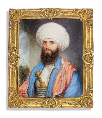 James Silk Buckingham, con camisa blanca, abrigo azul claro, chal rosa bordado alrededor de sus hombros y turbante blanco con un puñal asegurado en su faja, fondo de paisaje con una mezquita de John Jukes
