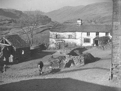 Tres niños observando los caballos en el corral de Kentmere con la granja y las colinas detrás. de Joseph Hardman