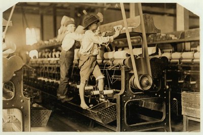 Niños pequeños trepando en el marco giratorio para arreglar hilos rotos y reemplazar bobinas vacías en Bibb Mill, Macon, Georgia, 1909 de Lewis Wickes Hine
