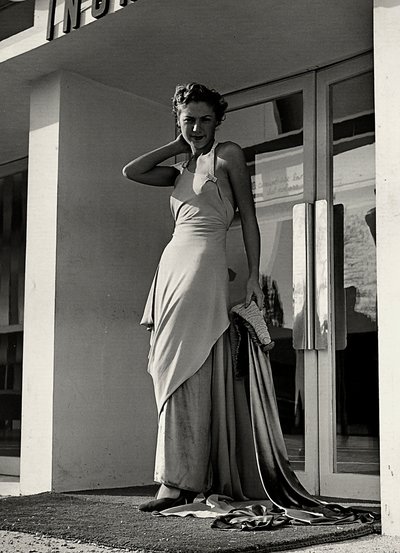 Modelo en vestido de noche creado por la casa de alta costura "Graldi". El artículo se caracteriza por un escote pronunciado adornado con tirantes de pedrería y una larga cola. de Luis Bogino