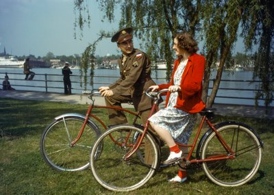 Sentados en bicicletas cerca de un puerto, un oficial del ejército estadounidense flirtea con una joven en Trini... de Luis Marden