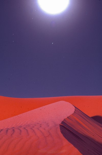 Las llamaradas sobre las dunas de arena del desierto brillan a medianoche cerca de la f... de Lynn Abercrombie
