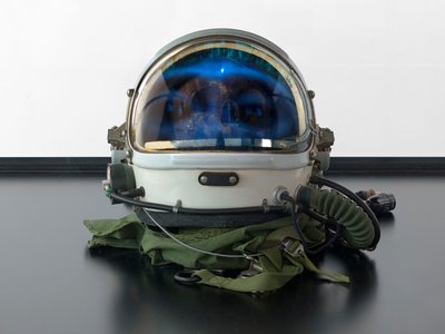 Alpha Omega, 2016 (cristal, pantalla LCD, reproductor multimedia, réplica de una calavera, casco espacial, madera) de Mat Collishaw