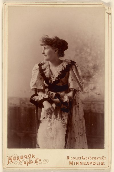 [Mujer no identificada de perfil, apoyada en una silla, sosteniendo un abanico de plumas] de Murdock and Company