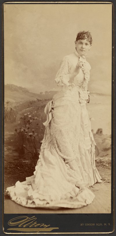 [Mujer no identificada con un largo y elegante vestido blanco, de pie] de Napoleon Sarony