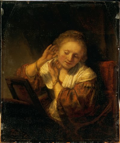 Joven mujer adornándose con pendientes de Rembrandt van Rijn
