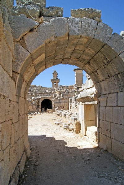 Vista a través de la entrada abovedada del teatro de Xanthos hacia el foso de la Orquesta, mostrando la columna y la tumba de la Arpía, Xanthos, Turquía de Roman