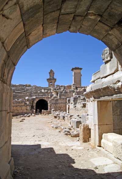 Vista a través de la entrada abovedada del teatro de Xanthos hacia el foso de la Orquesta, mostrando la columna y la tumba de Harpy, Xanthos, Turquía de Roman