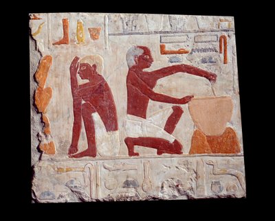 Arte egipcio antiguo: horneando pan. Un hombre hace la masa de pastel, otro supervisa el horneado de los moldes de pan. Piedra caliza (2500-2350 a.C.) 5ª dinastía. París, Museo del Louvre de School Egyptian