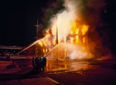 Un edificio urbano completamente envuelto en llamas y fuego por la noche en Kansas City con los bomberos de Ted Spiegel