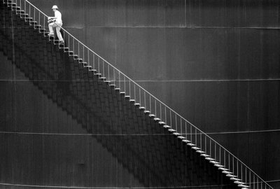 Un hombre sube los escalones de un tanque de almacenamiento de petróleo. de Ted Spiegel