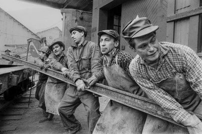 Trabajadores mineros se unen para mover un pesado raíl de acero en la mina de cobre El Teniente en... de Ted Spiegel
