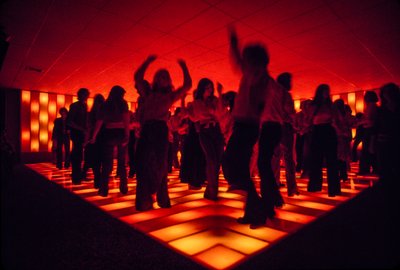 Jóvenes bailarinas en una discoteca bailando en una pista iluminada de Ted Spiegel