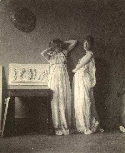 Dos modelos femeninas en traje clásico con la escultura 