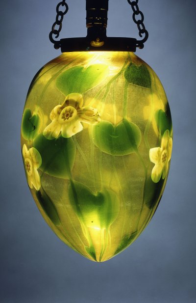 Una linterna colgante, decorada con hojas verdes y enredaderas y flores iridiscentes amarillas de Tiffany Studios