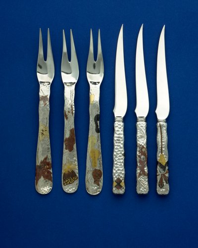 Parte de un fino y raro conjunto de 36 cuchillos y tenedores de postre, los mangos martillados con incrustaciones de cobre patinado y oro de varios colores, con detalles grabados de varios diseños florales, animales y geométricos, c.1880 de Tiffany and Company