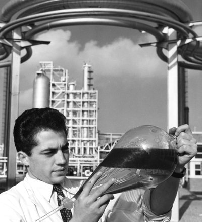 Un trabajador de laboratorio sostiene un embudo separador de aceite, refinería de Dunkerque, Francia, 1950s de Unbekannt