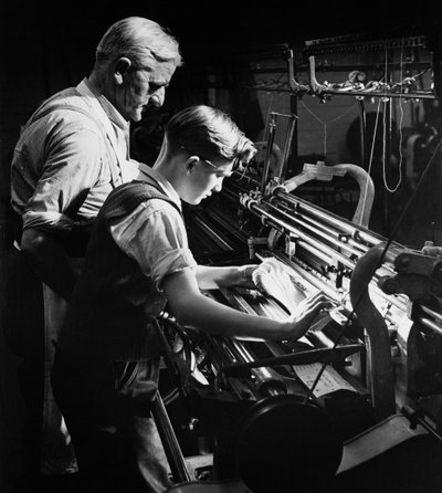 Un maestro entrena a un joven aprendiz en tejido a máquina, Lyle y Scott, Hawick de Unbekannt