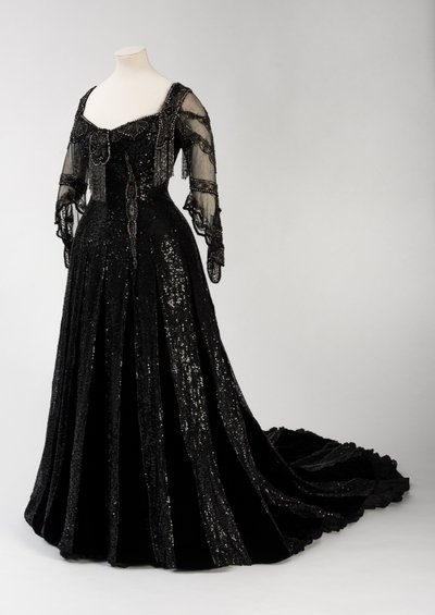 Vestido de noche negro de longitud completa usado por la Reina Alexandra, con decoración de cuentas y lentejuelas e incorporando la cinta de nombre de seda negra y letras doradas de la Reina Alexandra, hecho por Barolet de Knightsbridge, Londres 1908-1910 de Unbekannt