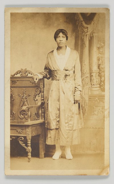Tarjeta postal fotográfica de una mujer junto a una silla de madera, 1904-1918 de Unbekannt