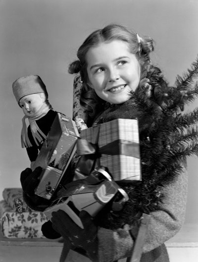 Niña llevando un montón de regalos de Navidad, c. 1950 de Unbekannt