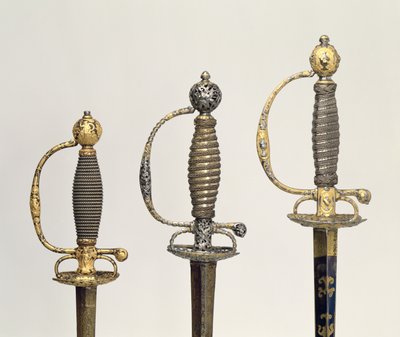 Empuñaduras de tres espadas francesas: una de acero, azulada y sobrepuesta con diseños en oro cincelado, c.1730; una de acero perforado y cincelado y el fondo de oro mate, c.1760; una de acero cincelado de Unbekannt Unbekannt