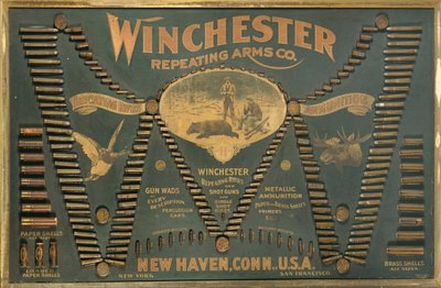 Tablero de exhibición de cartuchos Winchester, con una selección completa de cartuchos de rifle metálicos, de latón y de papel dispuestos en forma de una "W" extendida de Unbekannt
