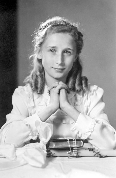 Niña cristiana con manos juntas en posición de oración con biblia, rosario y vela (foto de comunión). Fotografía alrededor de 1932 de Unbekannt