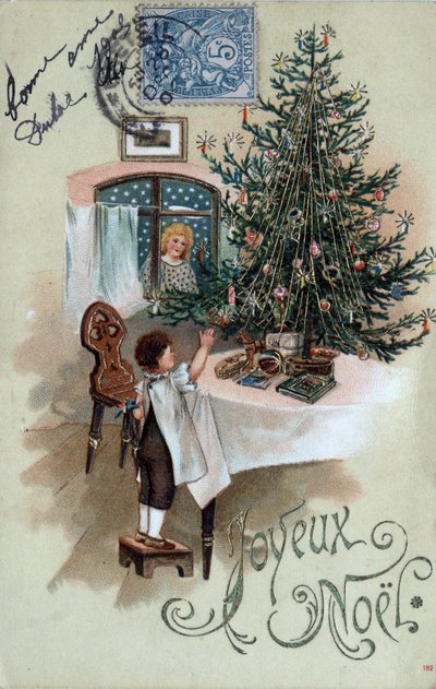 Tarjeta de felicitación navideña: un niño frente a un árbol de Navidad posa sobre una mesa, observado por un ángel en la ventana - Postal fechada en 1905 de Unbekannt