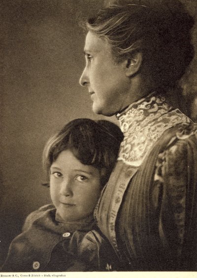 Retrato de medio cuerpo de un niño tiernamente abrazado por una anciana. La mujer posa de perfil, sosteniendo el pecho del pequeño. Tiene una mirada vivaz y pícara, que dirige hacia la cámara. de Unbekannter Künstler