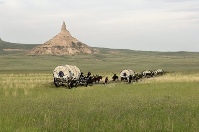 Historia de los colonos de West Conquete: Pioneros americanos. Viajes de varias familias cruzando las llanuras de Estados Unidos en diligencia. Diligencias cruzando Chimney Rock en el Camino de Oregón, Nebraska. Grabado en color combinado con una fotografí de Unbekannter Künstler