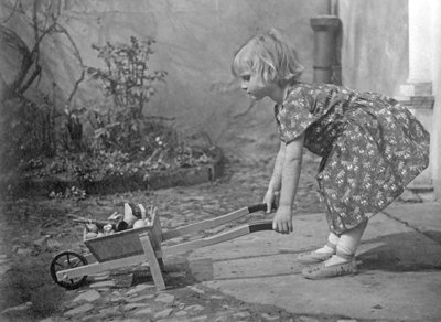 Niña pequeña jugando con una carretilla. Fotografía alrededor de 1931 de Unbekannt