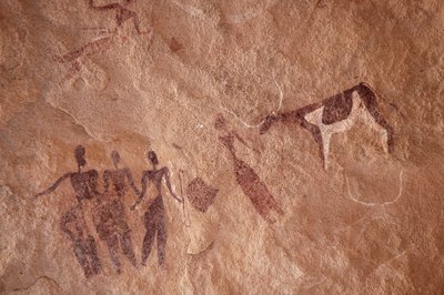 Arte rupestre, Prehistoria: Pintura rupestre de un grupo de personajes y una vaca bicolor con grandes cuernos en un refugio ornamentado, en el macizo de Uweinat, Egipto. (Período de 8000 a 3000 años a.C.). Fotografía de Unbekannt