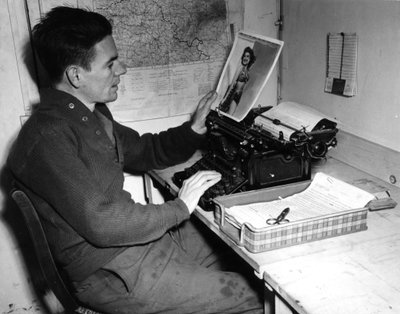 Segunda Guerra Mundial (1939-1945): Mutzig (Alsacia) Francia 1 de diciembre de 1944: El cabo Flanerty cronista del Beachead News (periódico de noticias de los GI) mira una fotografía de pin-up que publicará en el próximo número del periódico de Unbekannt