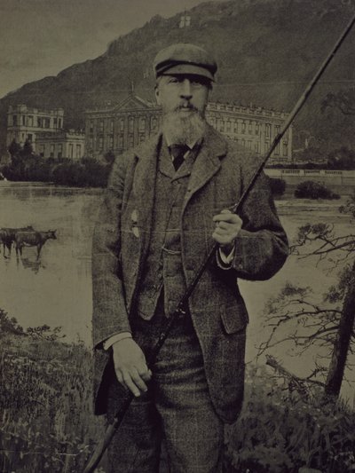 Retrato de estudio del 8º Duque de Devonshire con ropa de tweed sosteniendo una caña de pescar frente a una pantalla impresa que representa Chatsworth de William M. Timlin