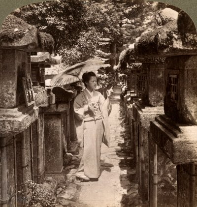 Una mujer devota sintoísta contando las linternas de piedra, Santuario Kasuga, Nara, Japón de Underwood and Underwood