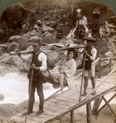 Mujer japonesa en una silla de montaña yamakago cruzando el torrencial río Daiya cerca de Nikko, Japón de Underwood and Underwood