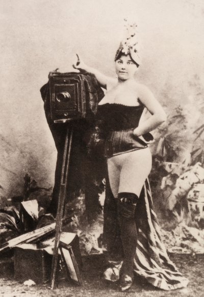 Retrato de una mujer parcialmente desnuda apoyada en una cámara antigua. de Unknown photographer