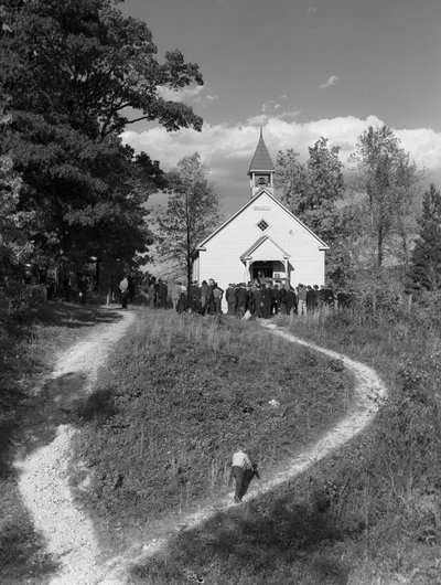 Hombres reunidos en el exterior de un pequeño edificio rural, una escuela o una iglesia con campana... de Volkmar Wentzel