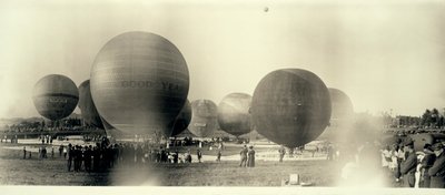 Globos de aire caliente en un campo en el sur de St. Louis listos para el lanzamiento; uno ya está en el cielo a lo lejos de W.C. Persons
