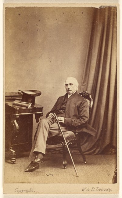 [Hombre de pelo blanco no identificado sentado, con bastón, sombrero de copa y un libro sobre la mesa a la izquierda]. de W. and D. Downey