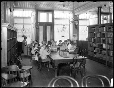 Niños leyendo en la sala de lectura de una sucursal no identificada de la Biblioteca Pública del Borough de Queens, c.1910 de William Davis Hassler