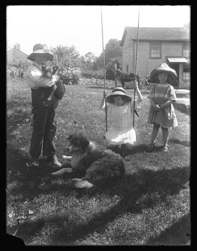 Niños con un perro y un cachorro reunidos alrededor de un columpio de cuerda en la granja McCready, Pensilvania, c.1913 de William Davis Hassler